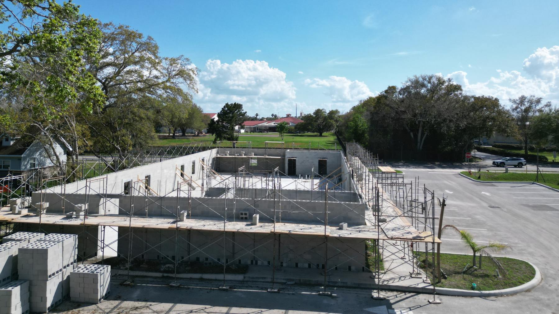 Concrete block walls of the new masjid rising, surrounded by scaffolding